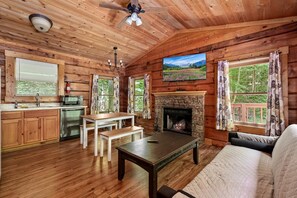 A log cabin interior with a fireplace, dining area, and a sofa. - Charming Romantic Cabin Escape with Private Hot Tub in Sevierville, Tennessee (Sevierville)