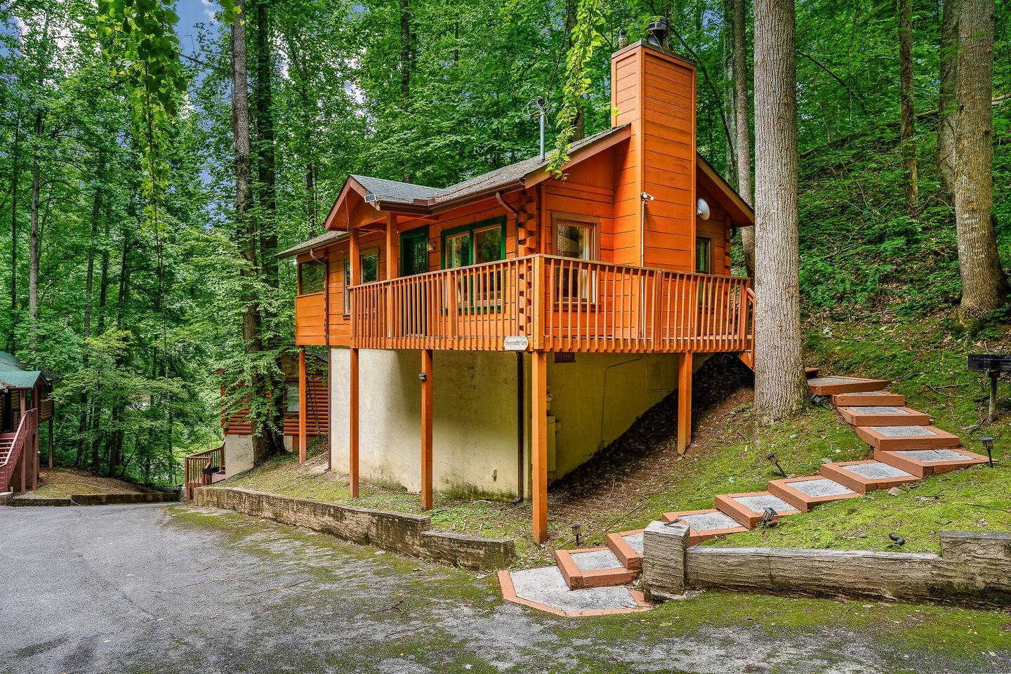 A cabin with a balcony, surrounded by forest.