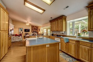 A spacious kitchen with wooden cabinets, a central island, and a large window providing natural light. - Spacious Family Retreat Near Zion National Park in Hurricane, Utah (Hurricane)