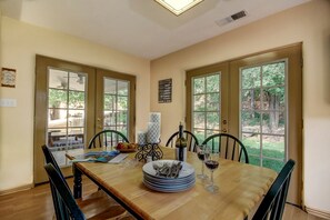 A dining area with a wooden table, chairs, and a view of the outdoors through large windows. - Spacious Family Retreat Near Zion National Park in Hurricane, Utah (Hurricane)
