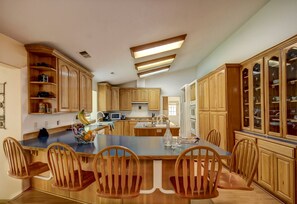 Una cocina con armarios de madera, una isla central con sillas y electrodomésticos integrados.