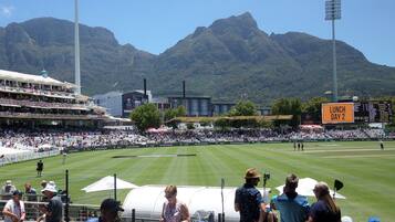A stadium with a large crowd, a scoreboard, and mountains in the background.