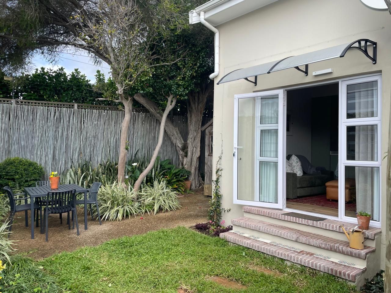 A residential property with a patio area, a sliding glass door entrance, and a small outdoor seating area.