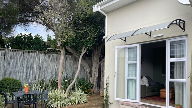 A residential property with a patio area, a sliding glass door entrance, and a small outdoor seating area. - Discover Cape Town from Your Stylish Upper Claremont Garden Cottage (Cape Town)