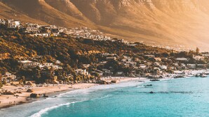 A coastal town with a beach, mountains, and residential buildings. - Discover Cape Town from Your Stylish Upper Claremont Garden Cottage (Cape Town)