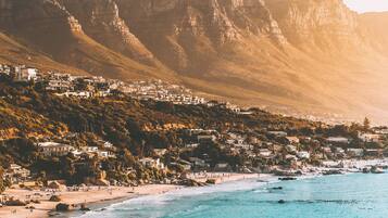 A coastal town with a beach, mountains, and residential buildings.