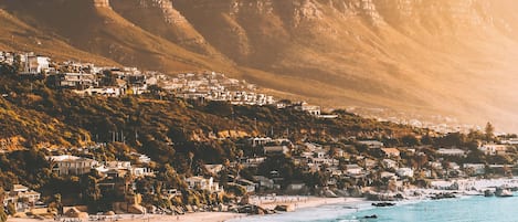 A coastal town with a beach, mountains, and residential buildings.