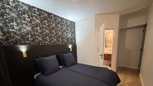 Ett sovrum med en mörk sänggavel, två sänglampor och en stor säng.