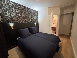 Ein Schlafzimmer mit einem dunklen Kopfteil, zwei Nachttischlampen und einem großen Bett.