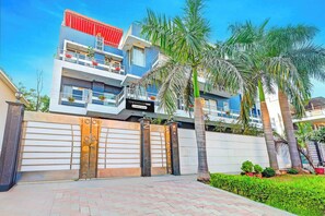 A modern multi-story building with a gated entrance, balconies, and a sign indicating it is a company-serviced property. - Townhouse Oak Omaxe City Centre Gurgaon (Gurugram)