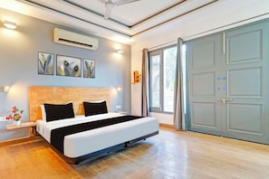 Un dormitorio moderno con cama, mesitas de noche, aire acondicionado instalado en la pared y un ventanal con cortinas.