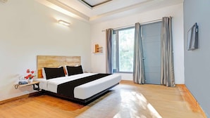 Un dormitorio moderno con una cama grande, una mesita de noche con lámpara, una ventana con cortinas y una luz en el techo.