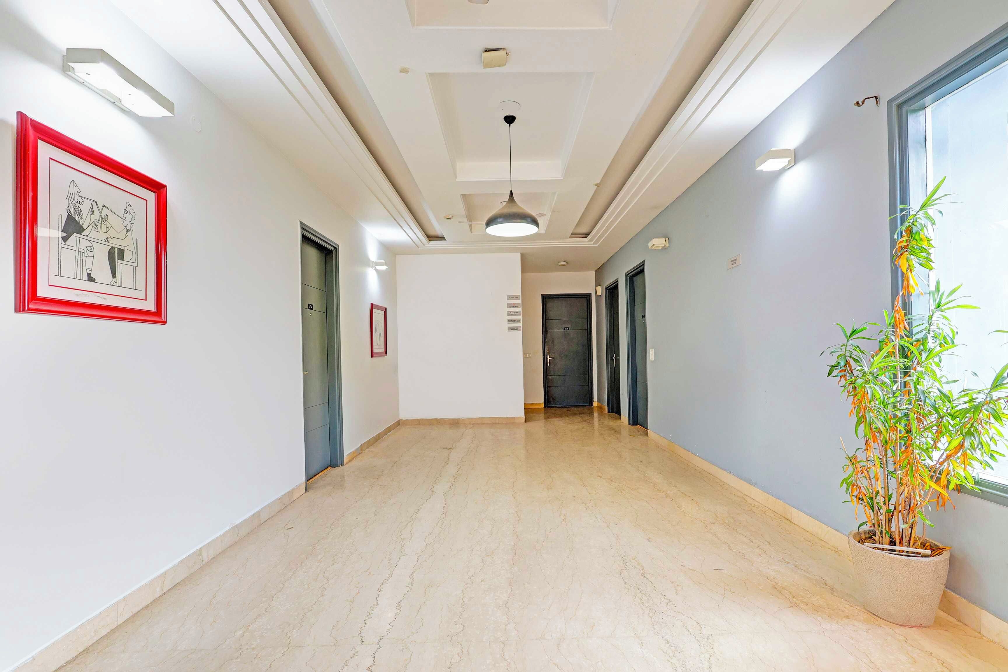 A hallway with a marble floor, a framed picture on the left, and a potted plant on the right.