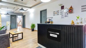 Zona de recepción con mostrador negro, un reloj y varios carteles, incluyendo 'Free Wi-Fi'.