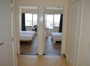 Ein Hotelzimmer mit zwei Betten, einem Fenster und Blick auf die Stadt.