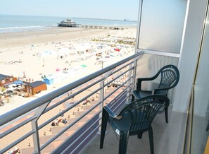 Ein Balkon mit Blick auf einen Strand, einen Steg und einige Strandsonnenstühle.
