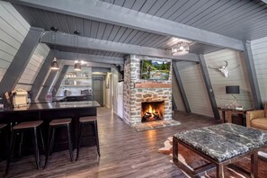 Um espaço de estar moderno estilo loft, com lareira de pedra, cozinha e bar com banquetas.