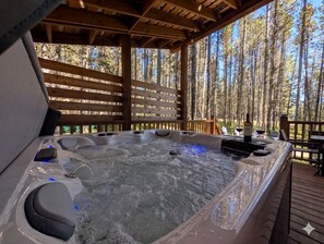 A hot tub with a wooden deck and a forest backdrop. - Modern A-Frame Cabin with Hot Tub Near Yellowstone, Island Park, Idaho (Island Park)