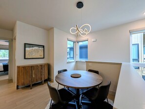 A modern dining area with a round table, black chairs, a wooden bench, and a pendant light. - NEW BUILD! King Bed | Shuttle to Slopes (Keystone)