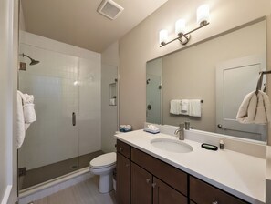 A modern bathroom with a shower, toilet, and vanity with a mirror. - NEW BUILD! King Bed | Shuttle to Slopes (Keystone)