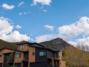 A modern two-story building with a flat roof and large windows, set against a backdrop of a clear blue sky and a mountain. - NEW BUILD! King Bed | Shuttle to Slopes (Keystone)