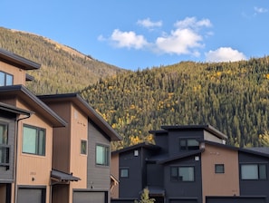 A modern residential area with multi-story buildings, a mountainous backdrop, and a clear sky. - NEW BUILD! King Bed | Shuttle to Slopes (Keystone)