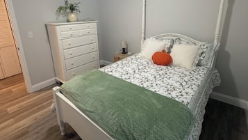 A bedroom with a bed, a dresser, a nightstand, and a ceiling light.