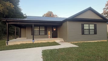 A two-story building with a covered porch, a garage, and a front door.