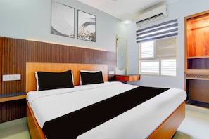 Een moderne slaapkamer met een houten hoofdeinde, een groot bed met zwart-wit beddengoed, twee kunstwerken aan de muur, een airconditioning en een raam met zonwering.