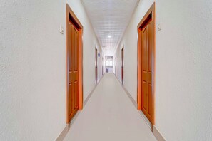 Un long couloir étroit, avec des portes de part et d’autre, qui mène à une pièce au fond.