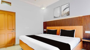 Una habitación de hotel con un cabecero de madera, ropa de cama blanca y dos obras de arte colgadas en la pared.