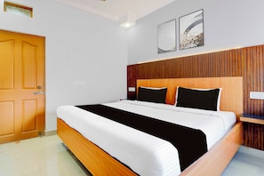Een hotelkamer met een houten bedframe, wit beddengoed en twee kunstwerken aan de muur.