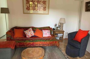 Ein Wohnzimmer mit einer Couch, einem Sessel, einer Lampe und einem Gemälde an der Wand.