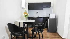 A compact kitchen with dark cabinets, a white sink, and a small refrigerator. - Leonida Residence (TARANTO)