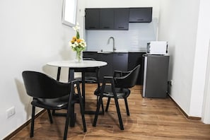 Een compacte keuken met donkere kastjes, een witte spoelbak en een kleine koelkast.