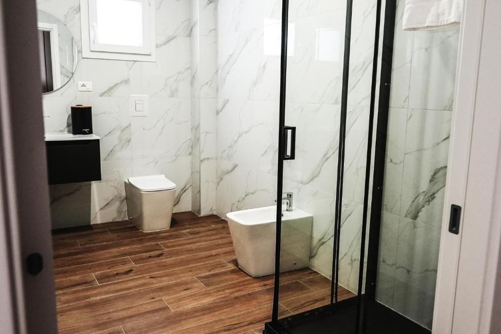 Ein Badezimmer mit Toilette, Bidet und einer Duschkabine aus Glas.