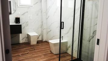 Ein Badezimmer mit Toilette, Bidet und einer Duschkabine aus Glas.