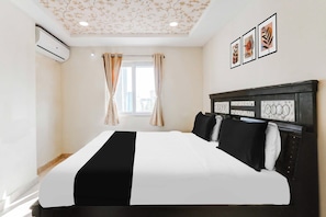 Una habitación de hotel con cama, cortinas, una ventana y decoración en la pared.