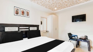 Hotellihuone, jossa on sänky, työpöytä, vaatekaappi ja televisio.