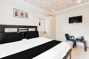 Habitación de hotel con cama, escritorio, armario y televisor.