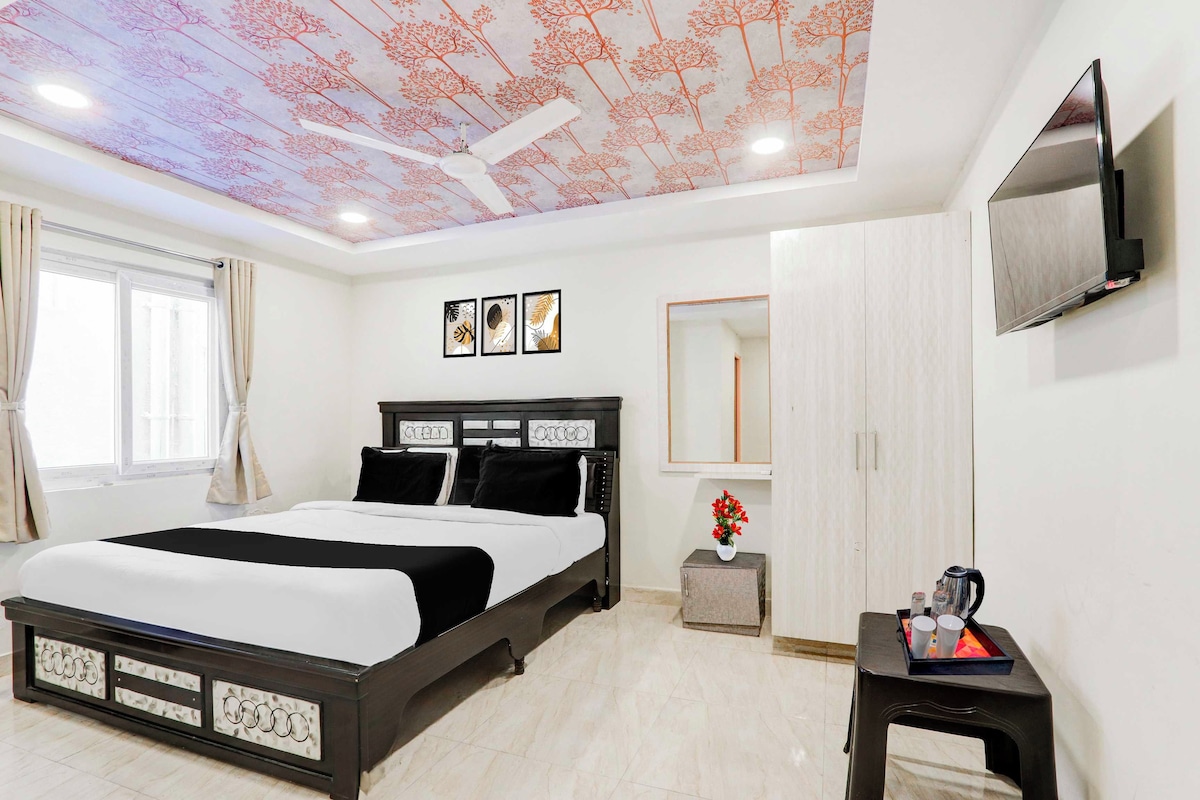 Un dormitorio moderno con cama, televisor, techo con motivos de árboles y obra de arte en la pared.