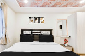Un dormitorio con cama, mesita de noche, espejo y cuadros en la pared.
