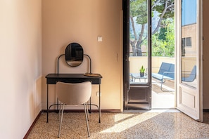 A room with a desk, chair, and a mirror. There is a door leading to an outdoor area with a table and chairs. - ZAGARA DI MARE (Palermo)