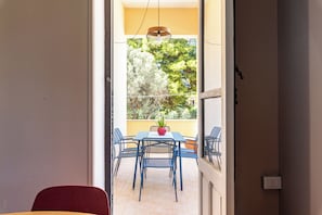 An open balcony with a table and chairs, a potted plant, and a view of trees. - ZAGARA DI MARE (Palermo)