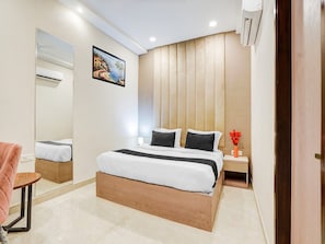 A modern bedroom with a wooden bed frame, a bedside table with a vase, and a large mirror.
