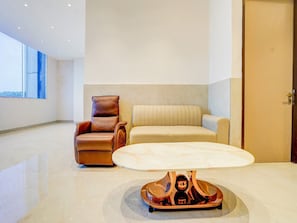 A modern living room with a leather armchair, a sofa, and a unique coffee table.