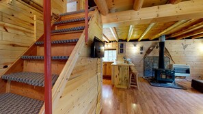 Ein Holzinnenraum mit Treppe, einer Küchenzeile und einem Kamin.