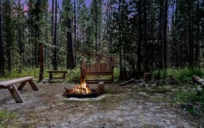 Ein Campingplatz mit Feuerstelle, Picknicktisch und Bank.