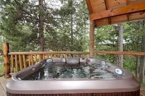 A hot tub on an outdoor deck with a wooden railing, surrounded by trees. - Scenic Island Park Cabin with Private Hot Tub & ATV Access Near Yellowstone, Idaho (Island Park)