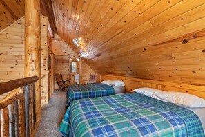 Une cabine avec deux lits, un plafond en bois et un petit coin salon.